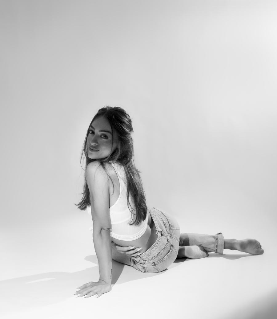 Black and white — seated on a white seamless, looking back over the shoulder