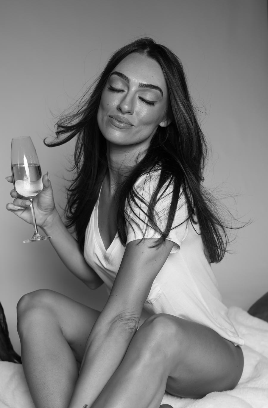 Black and white — eyes closed, a glass of champagne in hand