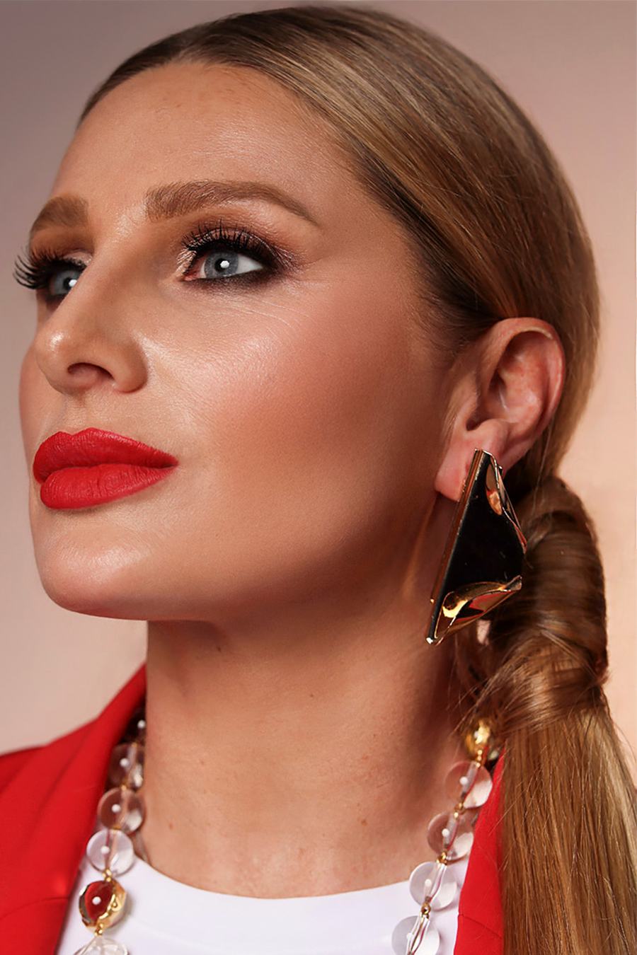 Close beauty profile — red lips, sculptural gold earring, hair drawn back