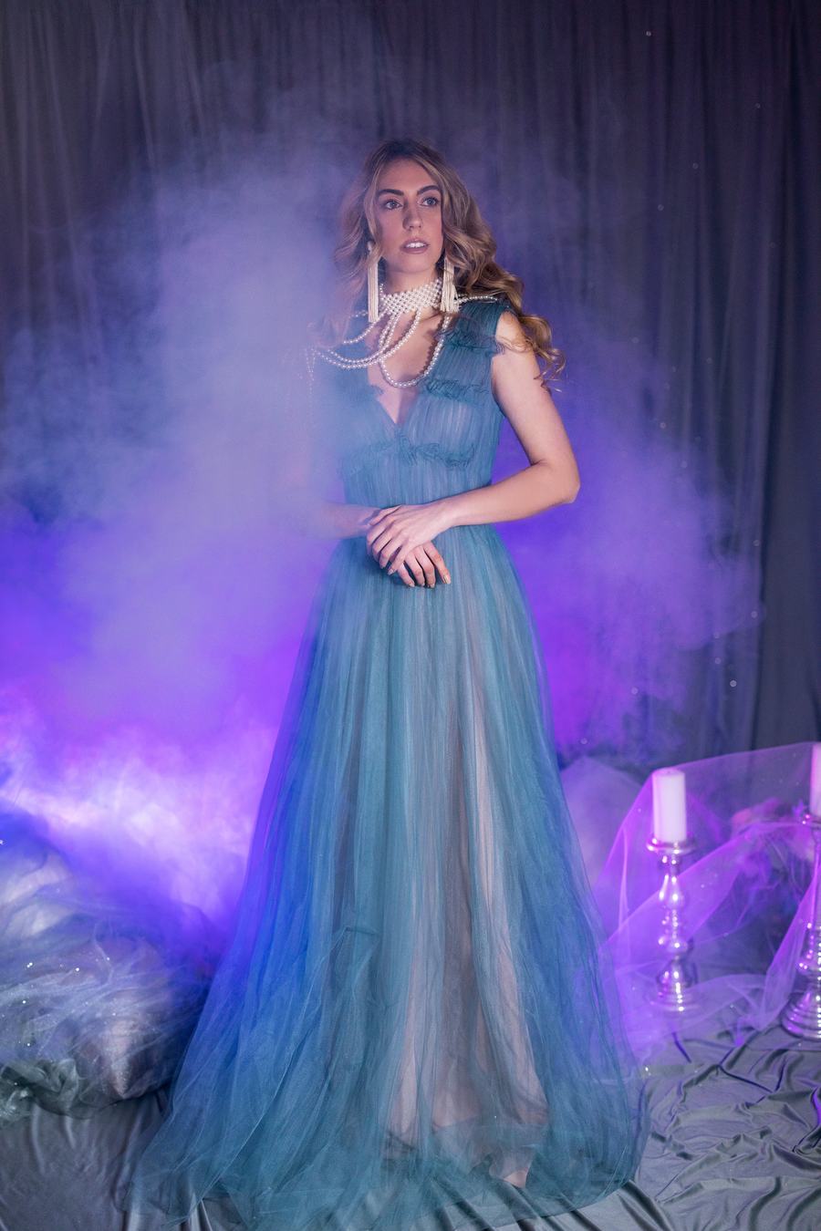 A blue tulle gown in violet smoke, candles beside her
